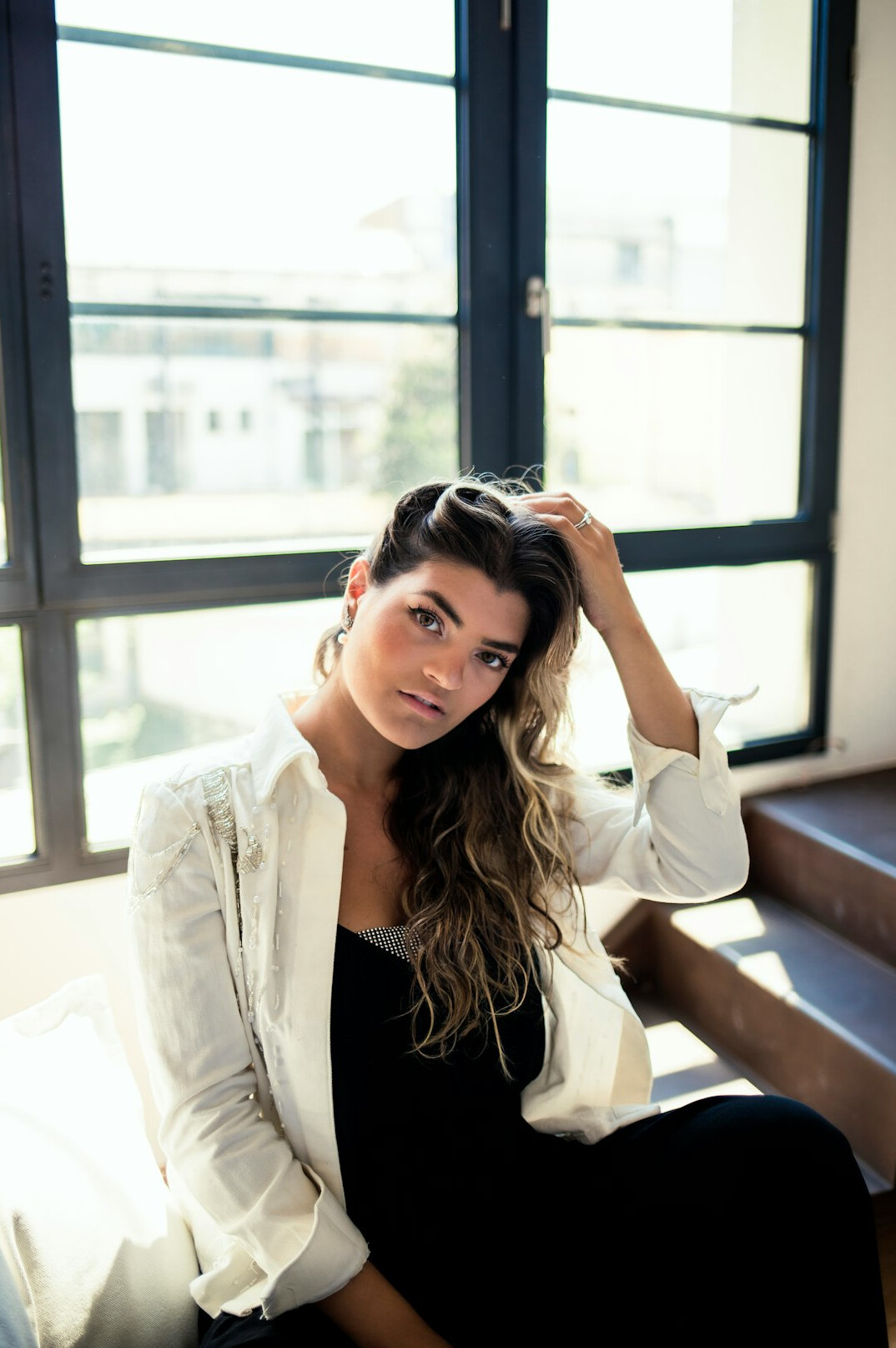 Studio portrait of a Portuguese woman in her fifties smiling warmly under stage lights